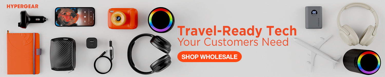 A promotional banner for Hypergear showcasing various travel-ready tech accessories, including an orange power bank, a smartphone, a compact camera, earplugs, headphones, a power adapter, and a pair of white over-ear headphones, arranged on a light gray background with promotional text.